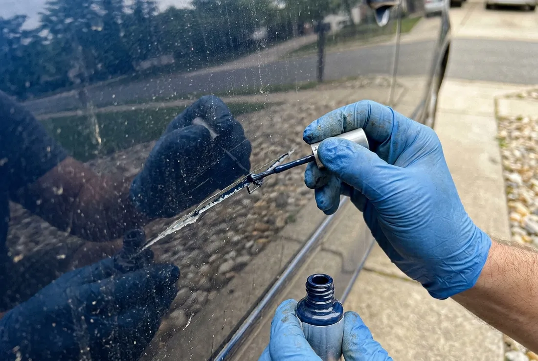 Technician buffing out a paint scratch on a car door in San Dimas